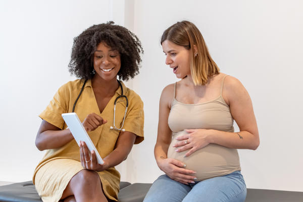 a pregnant person and a doctor looking at a tablet