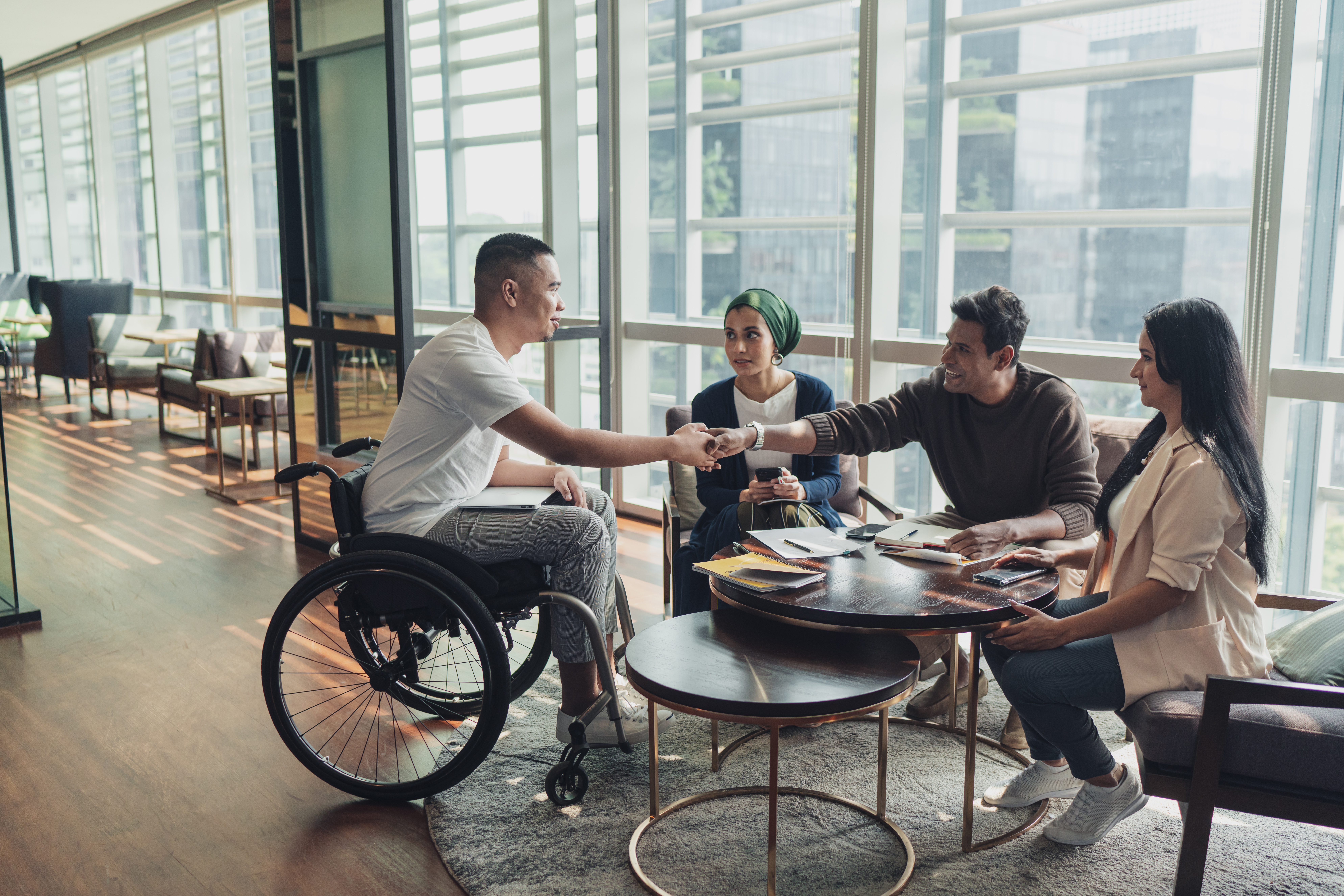 a man in a wheelchair shaking hands with a group of people