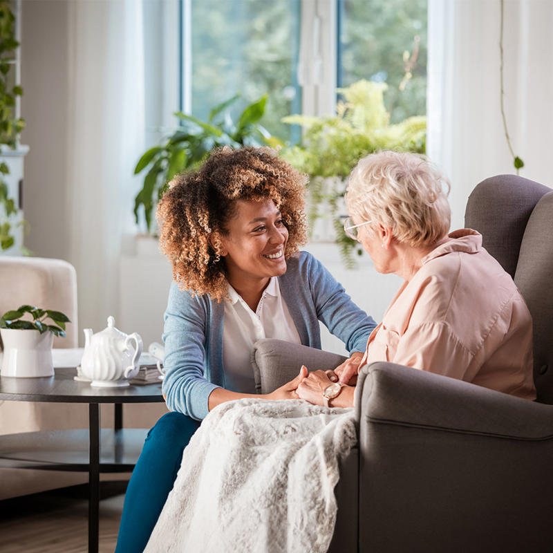 A nurse sits on a couch with an older woman