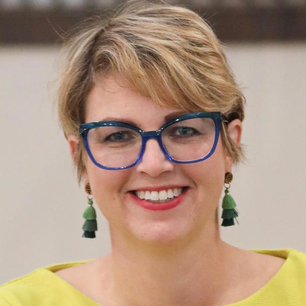 a woman wearing blue glasses and a yellow shirt