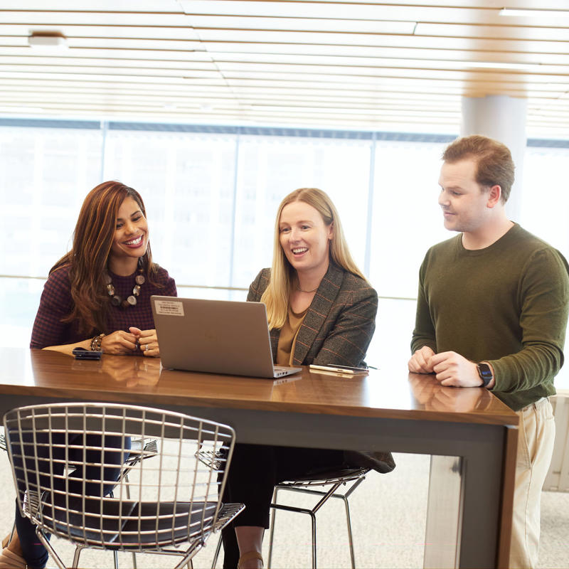 a group of people sitting at a table with laptops