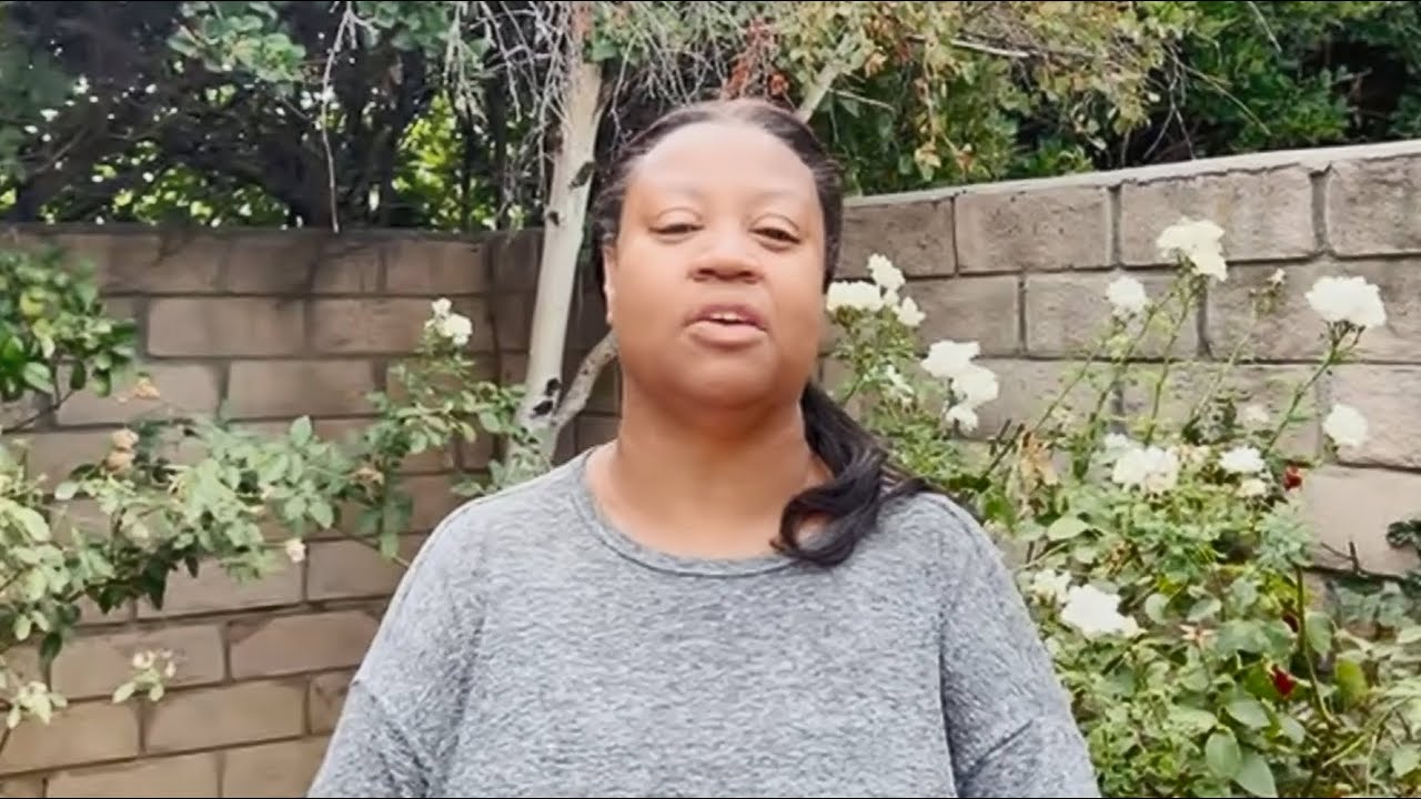 a woman standing outside in front of a brick wall