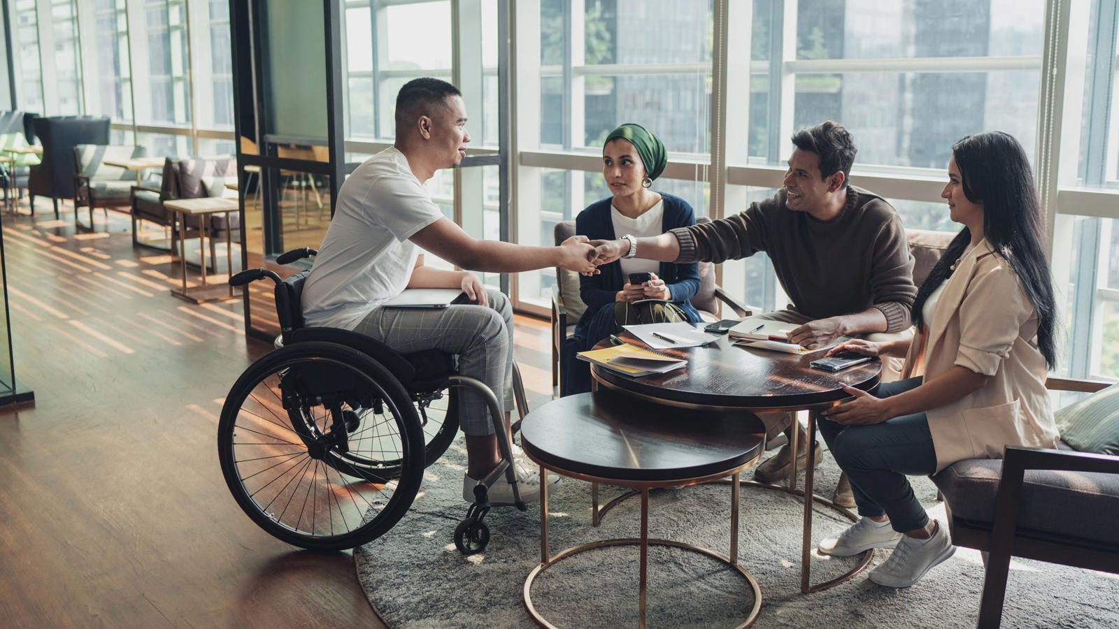 a man in a wheelchair shaking hands with a group of people
