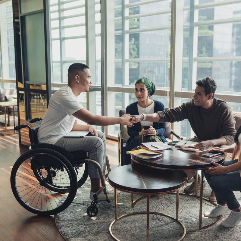 a man in a wheelchair shaking hands with a group of people