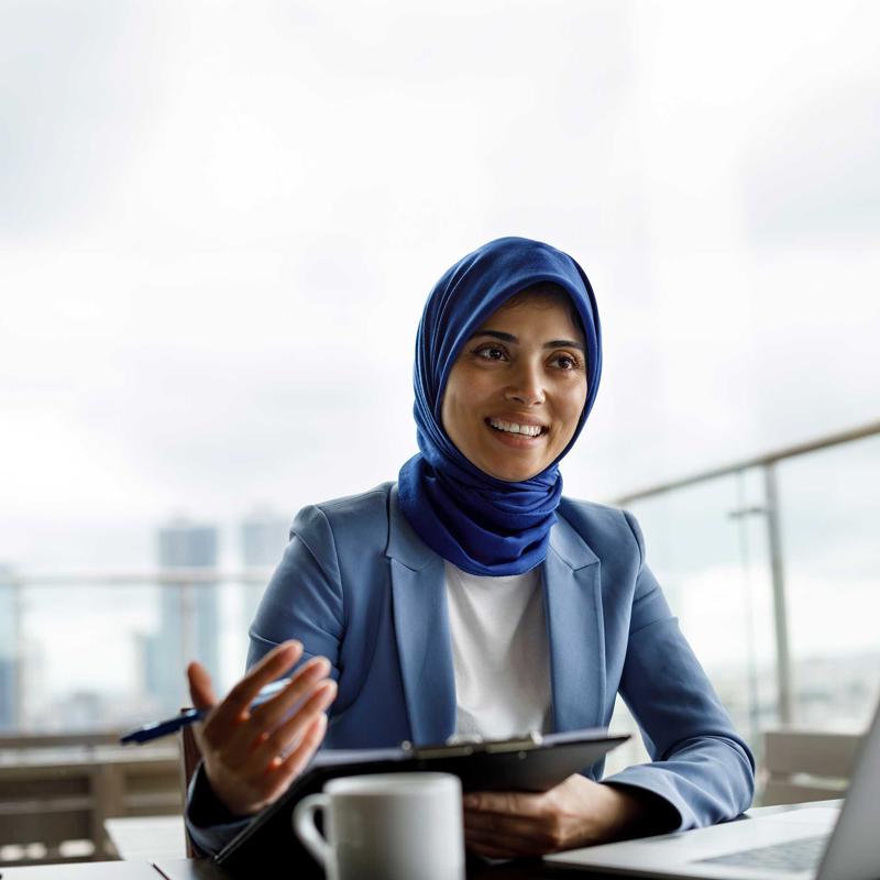 A woman in a headscarf gestures while speaking.