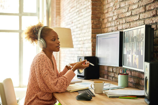 A woman wearing headphones speaks on a video call.