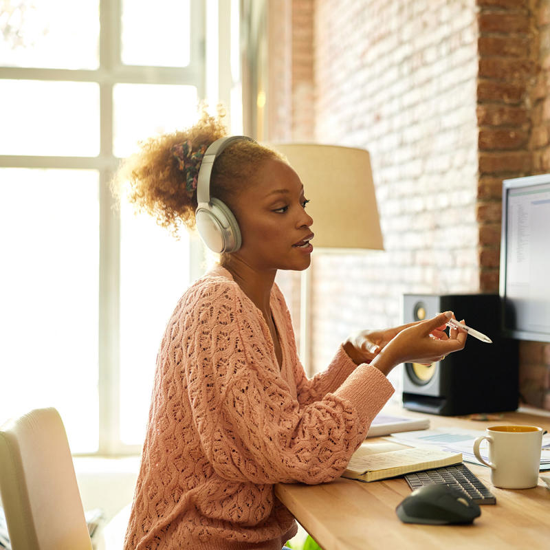 A woman wearing headphones speaks on a video call.